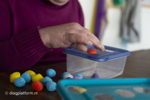 vrouw stopt gekleurde balletjes in een bakje